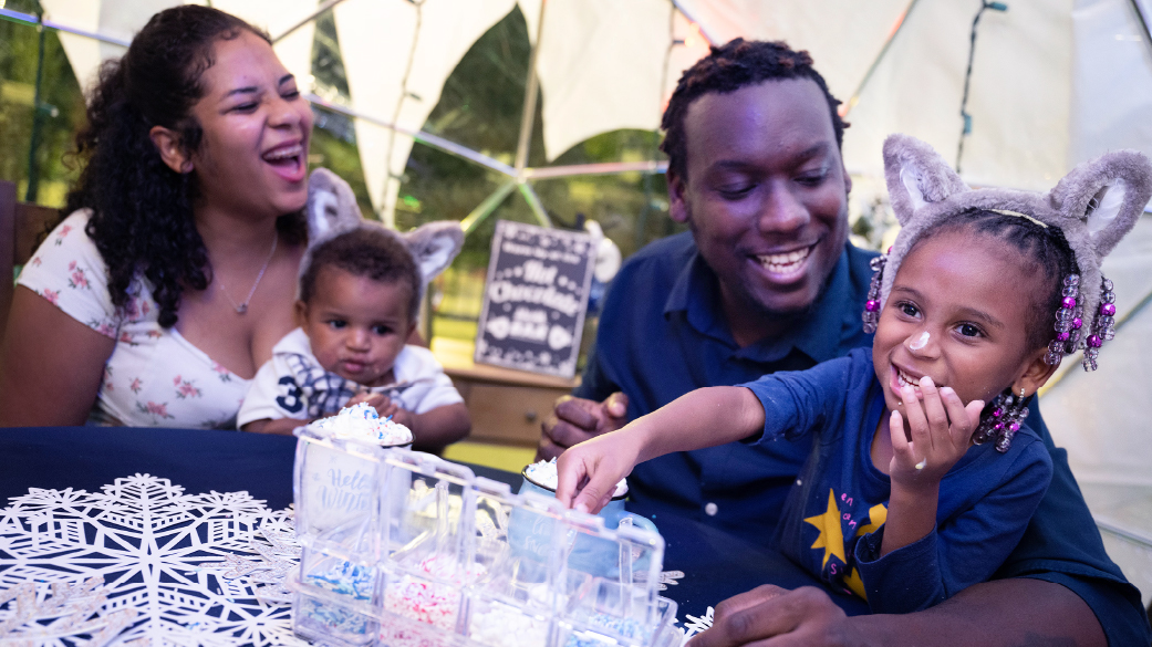 Family of four smiling and laughing inside a snow globe
