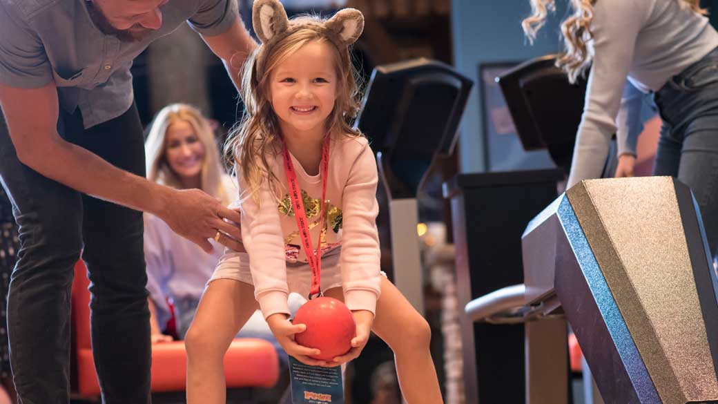 Little girl smiling while playing bowling