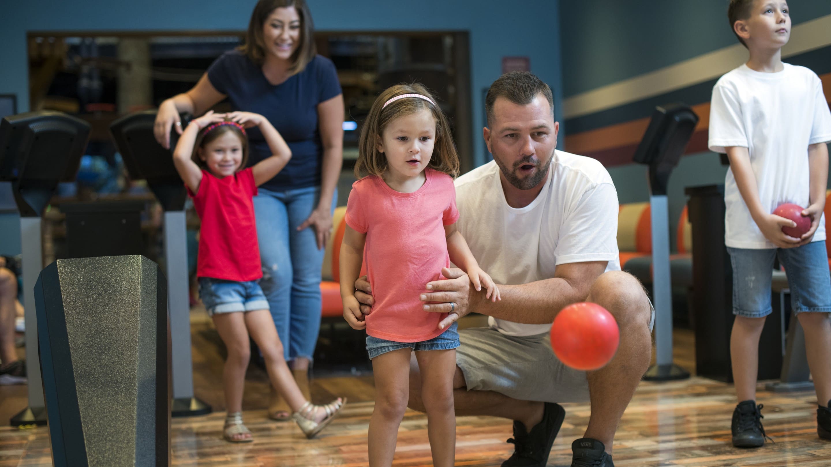 Dad helping young daughter bowl
