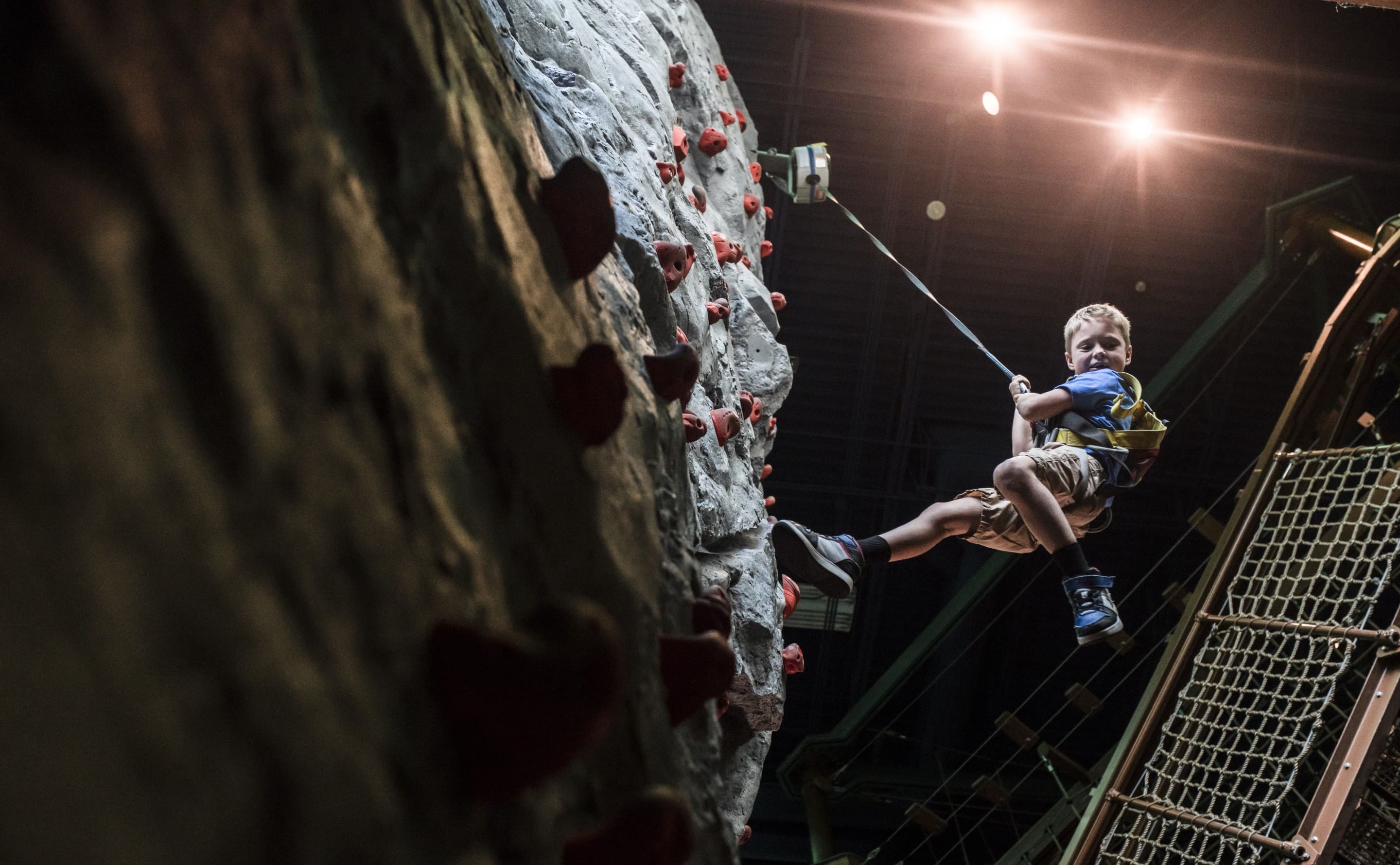 Child hanging by harness after climbing rock wall