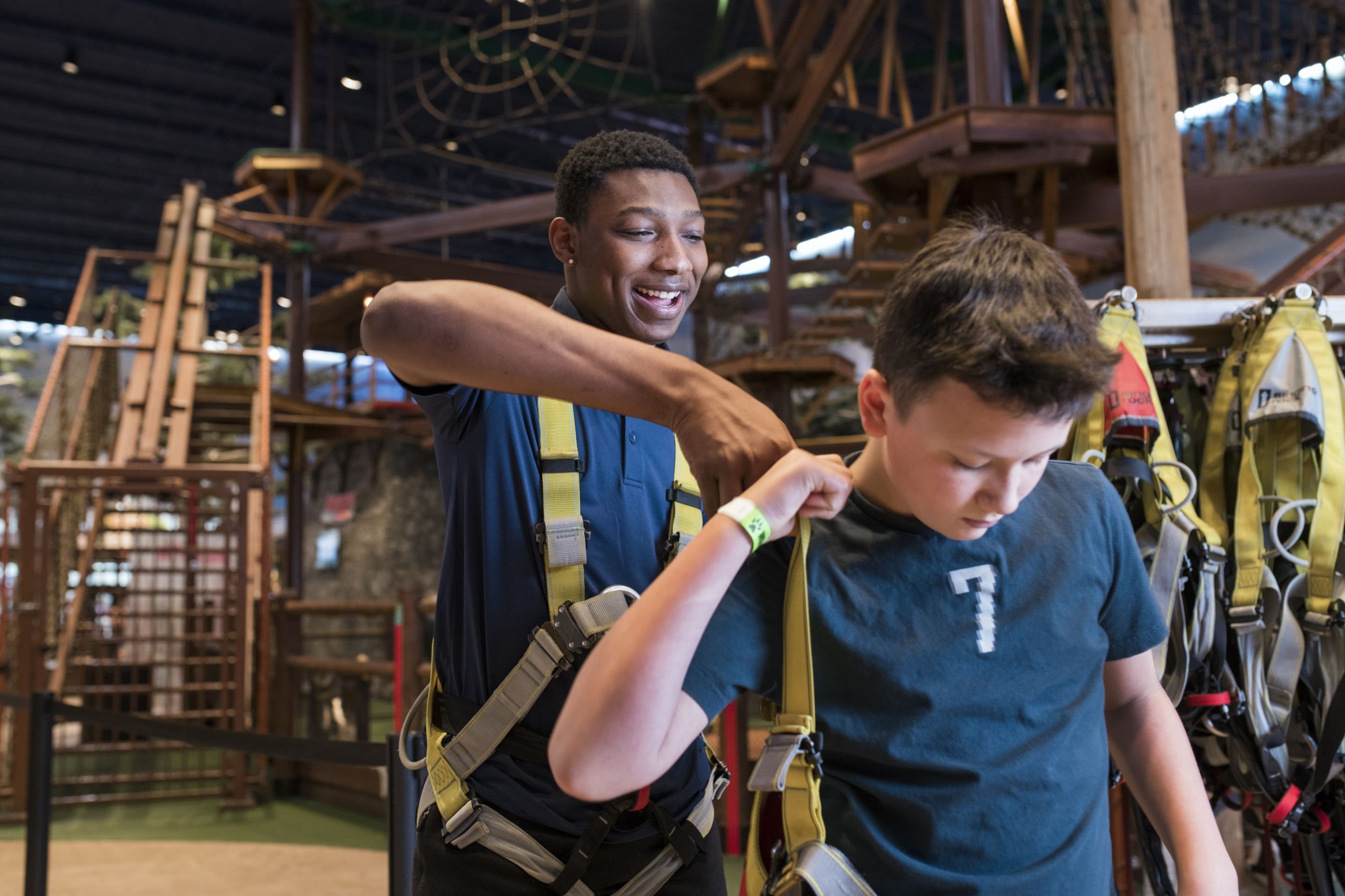 Staff member helps boy put on safety harness