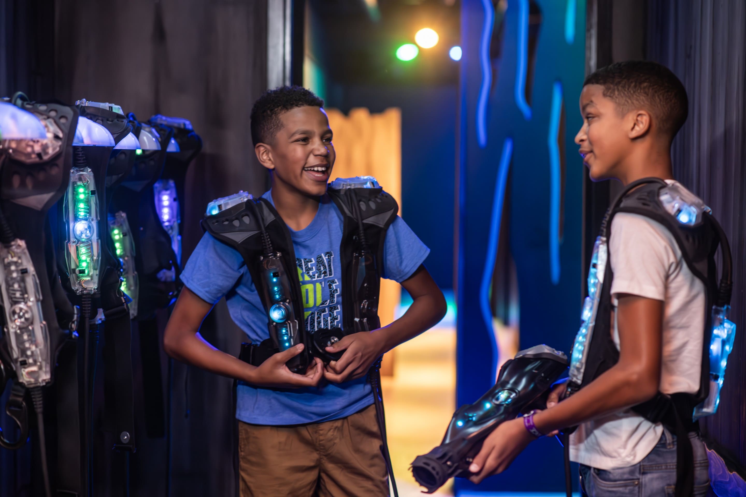 Two boys laughing while gearing up for laser tag