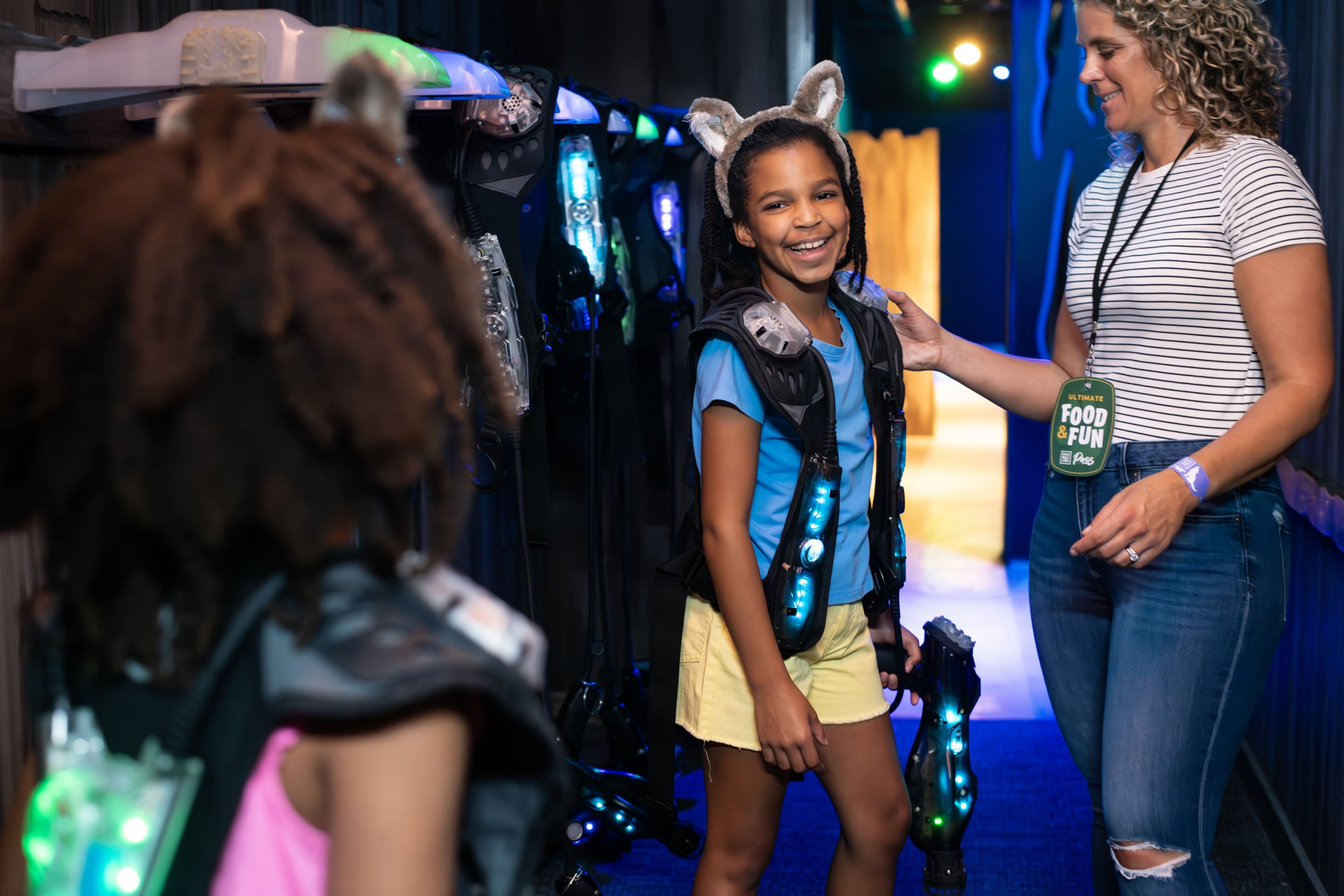 Kids smiling in laser tag gear with adult