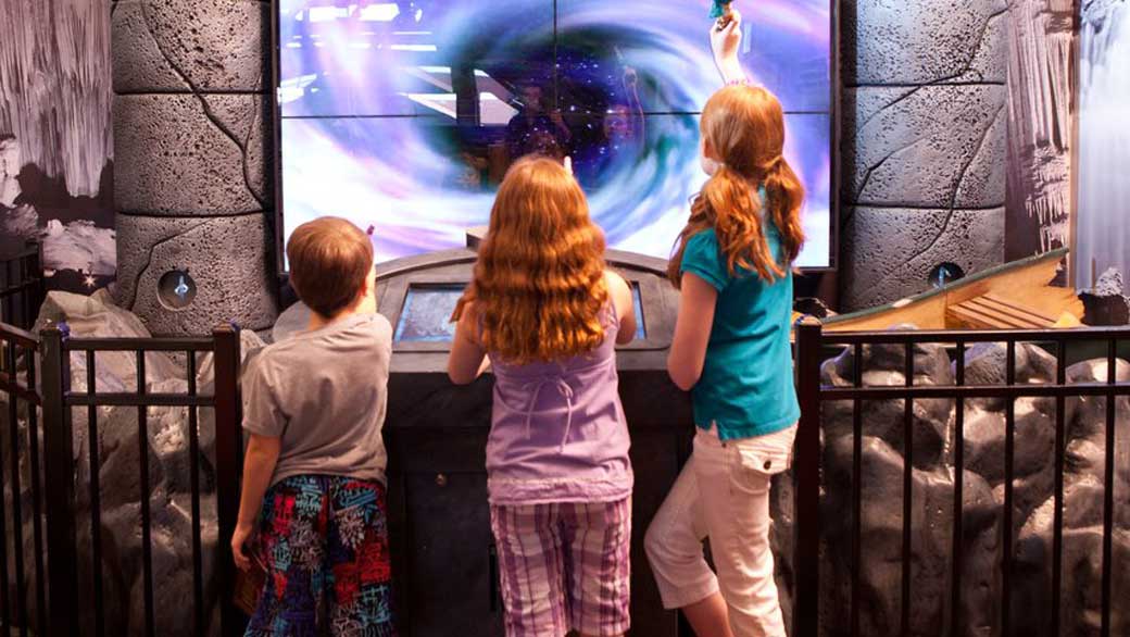 Boy wearing cape points wand into the sky