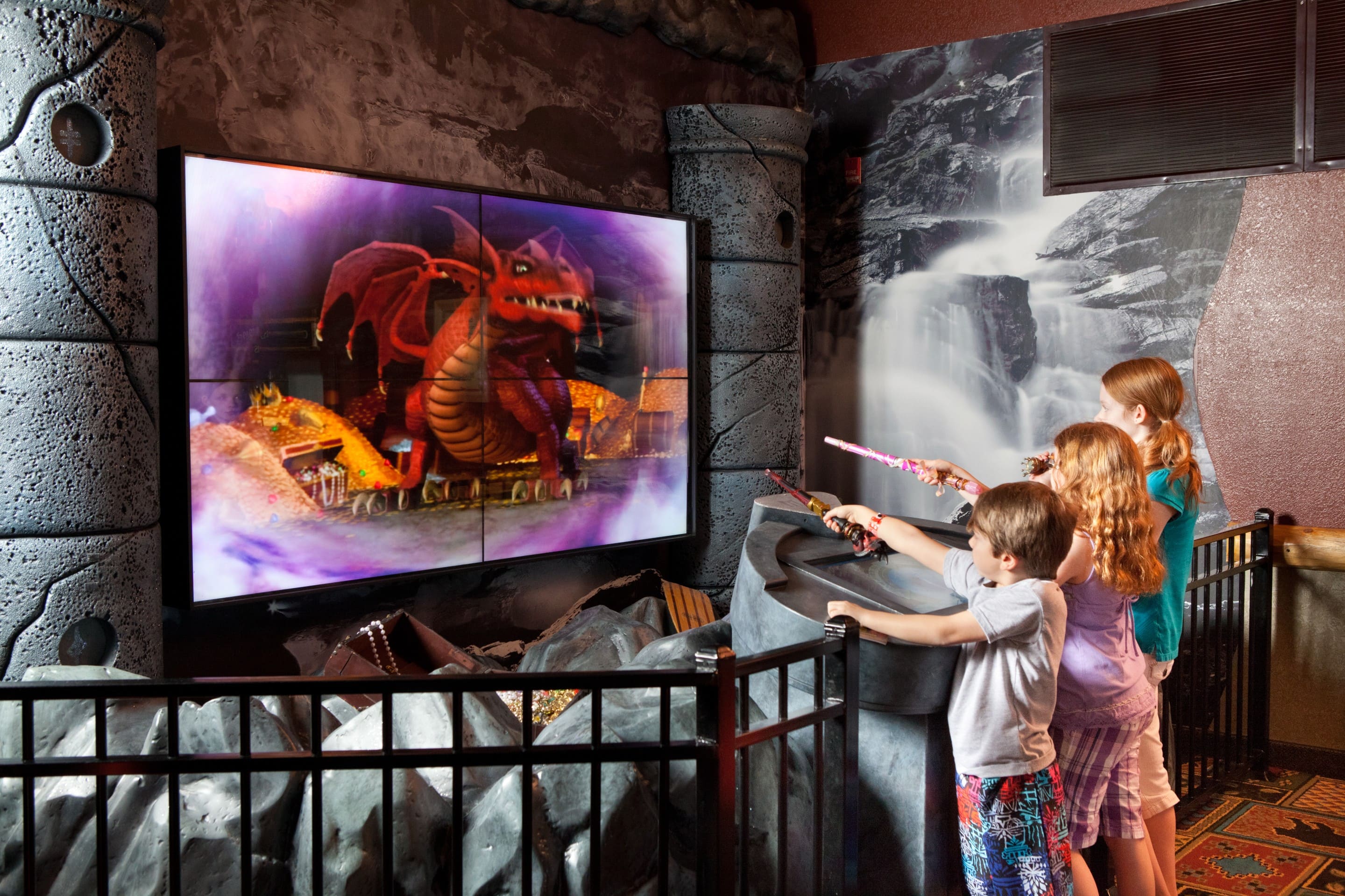 Three children pointing their wands at a digital interactive station in MagiQuest.