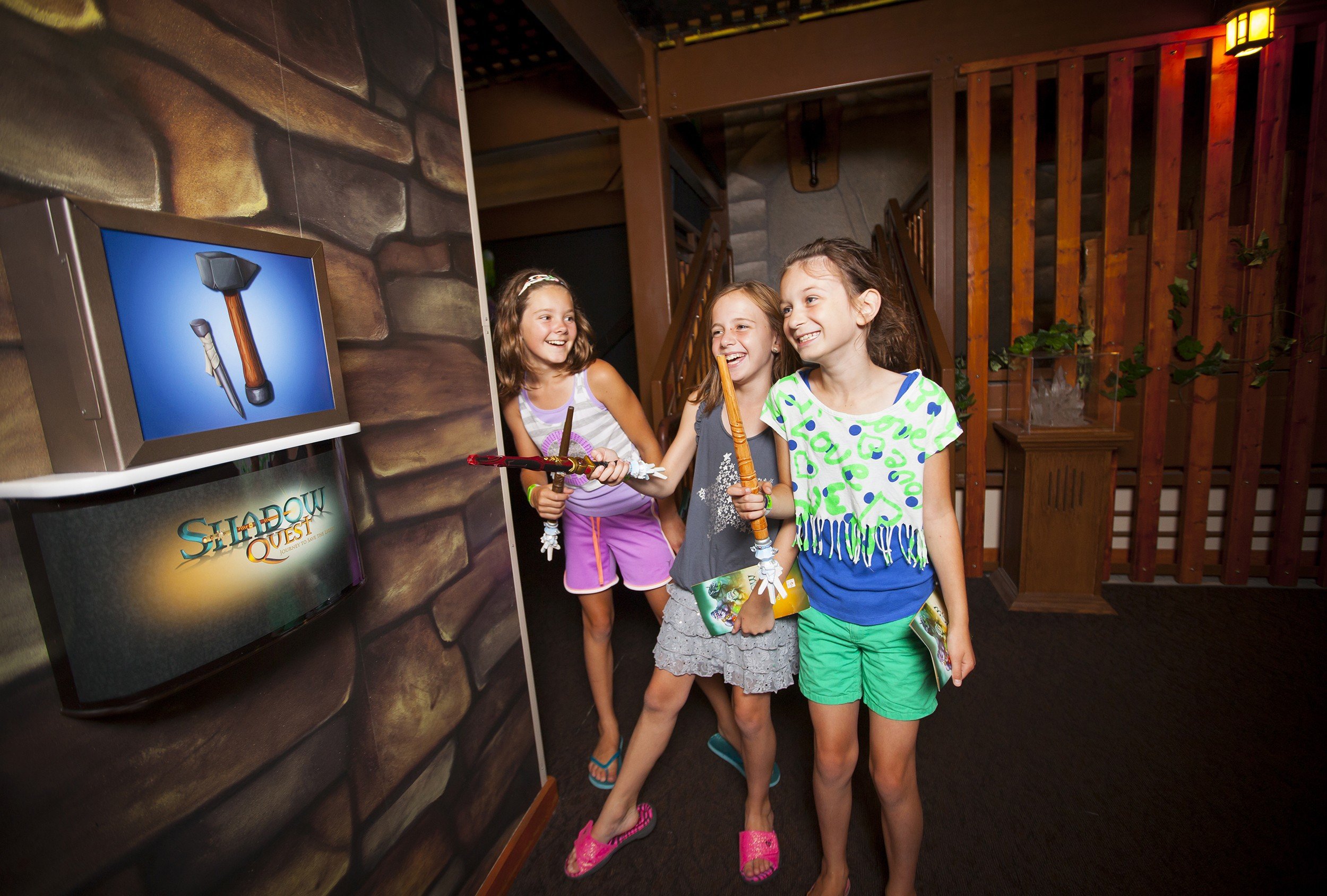 Three young girls with wands interacting with Shadow Quest screen