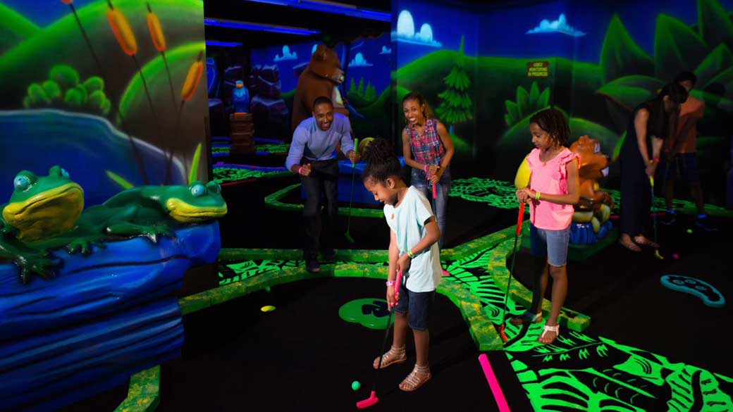 A family plays glow in the dark mini golf at Great Wolf Lodge