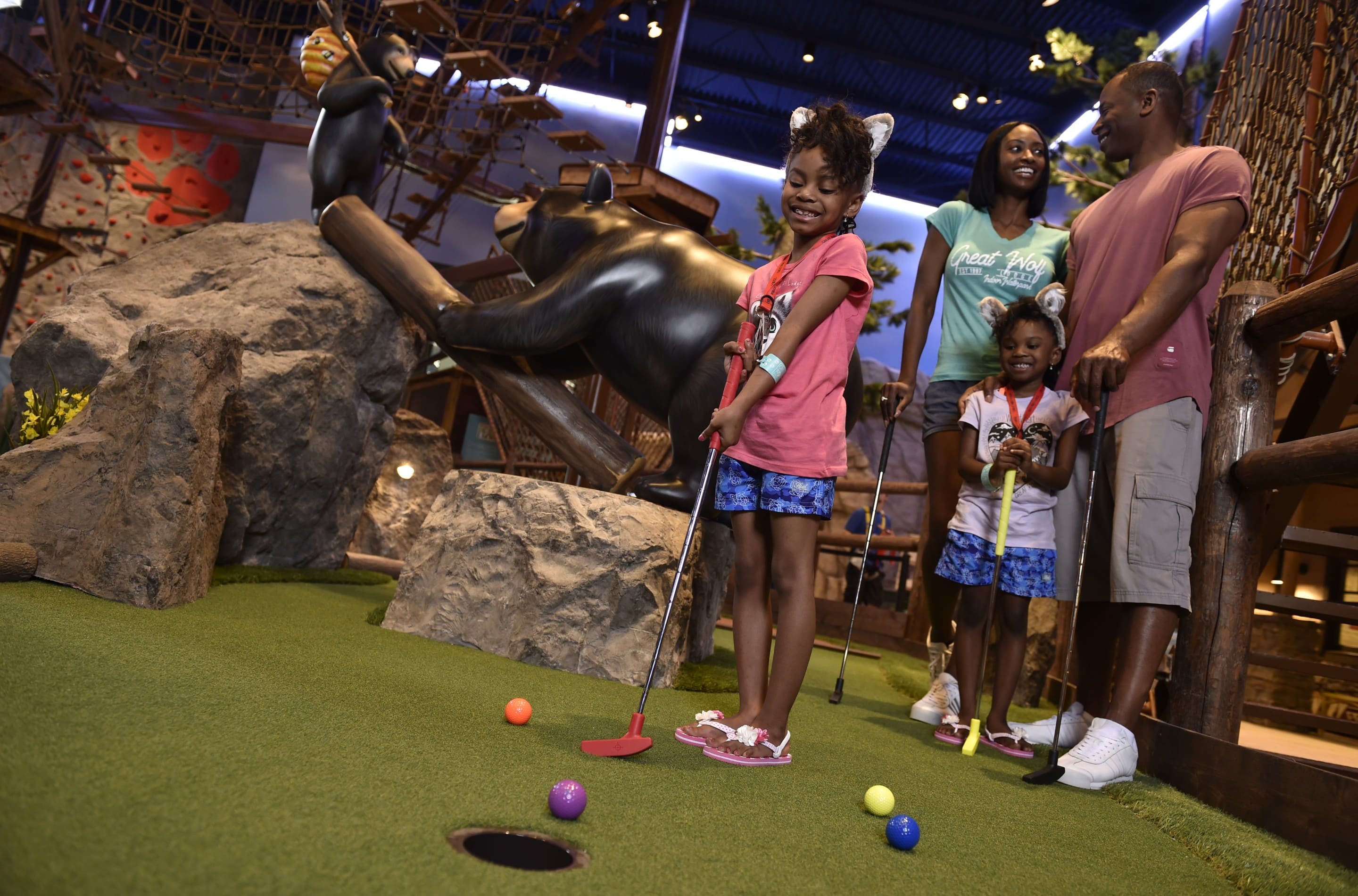 Young daughter putting while family looks on