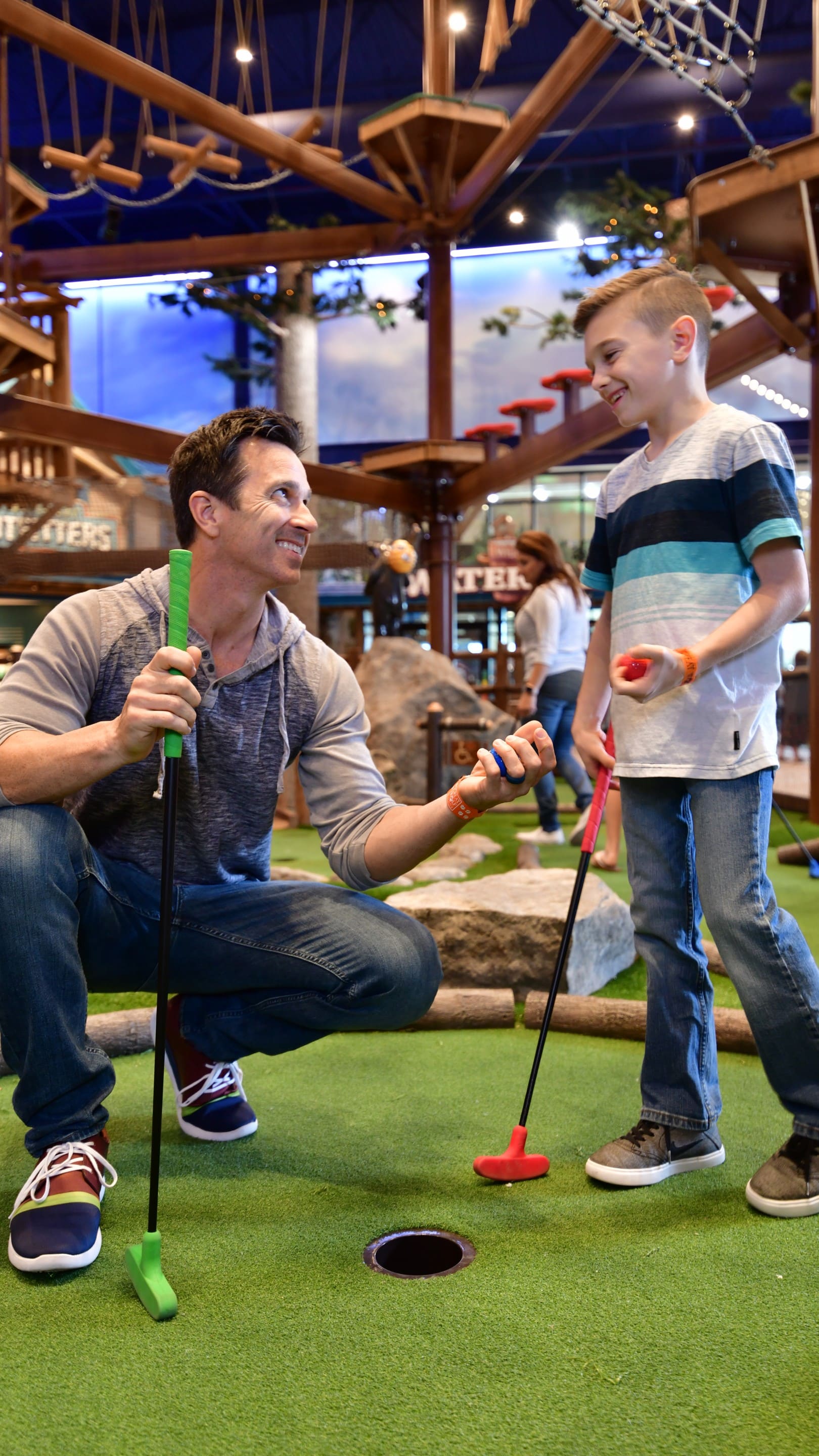 A dad helping his child putt