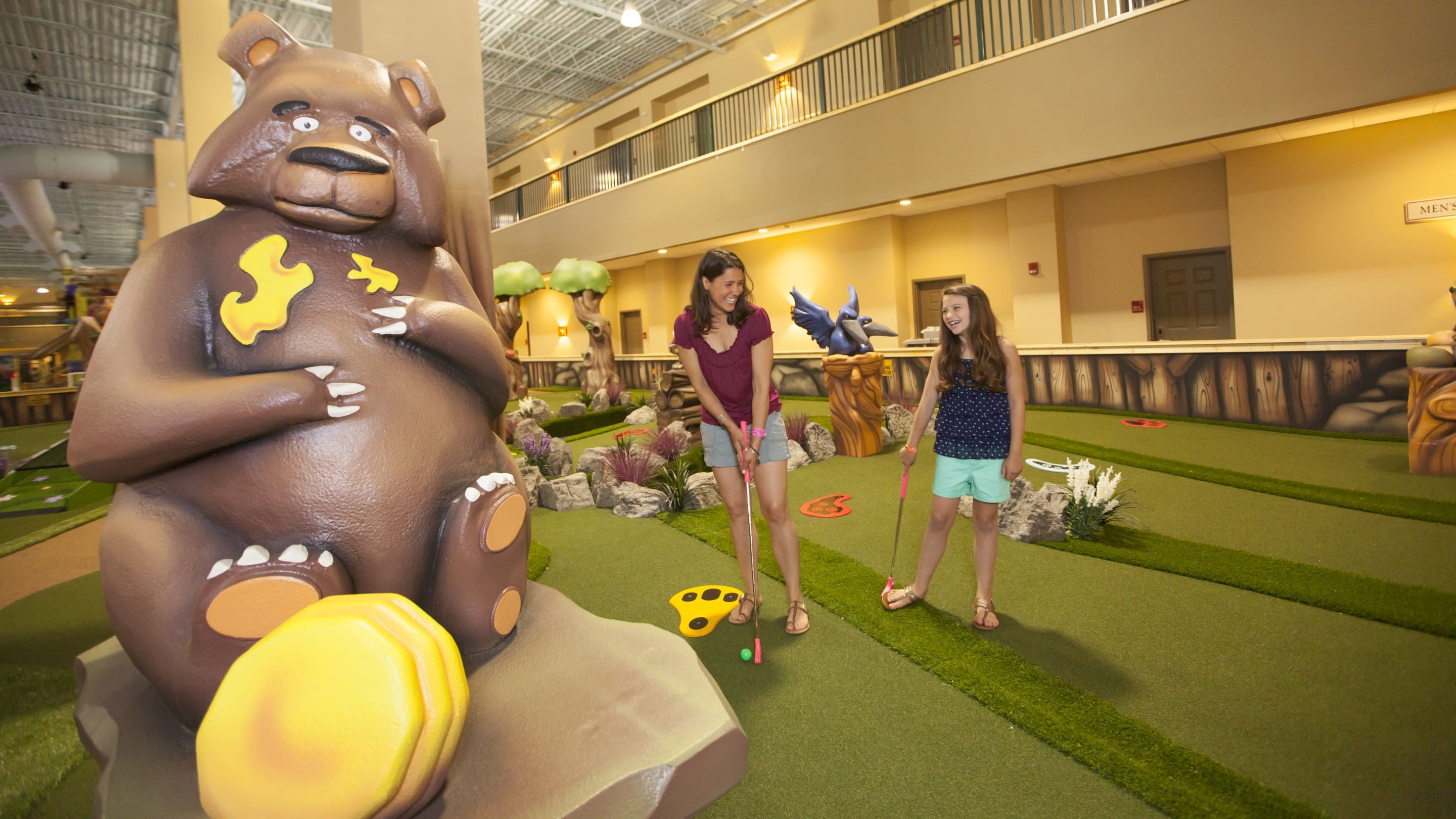 Mother and her daughter playing indoor mini golf