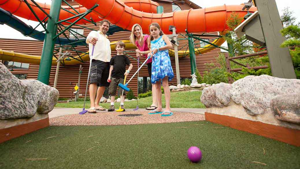 Family of four enjoying playing mini golf