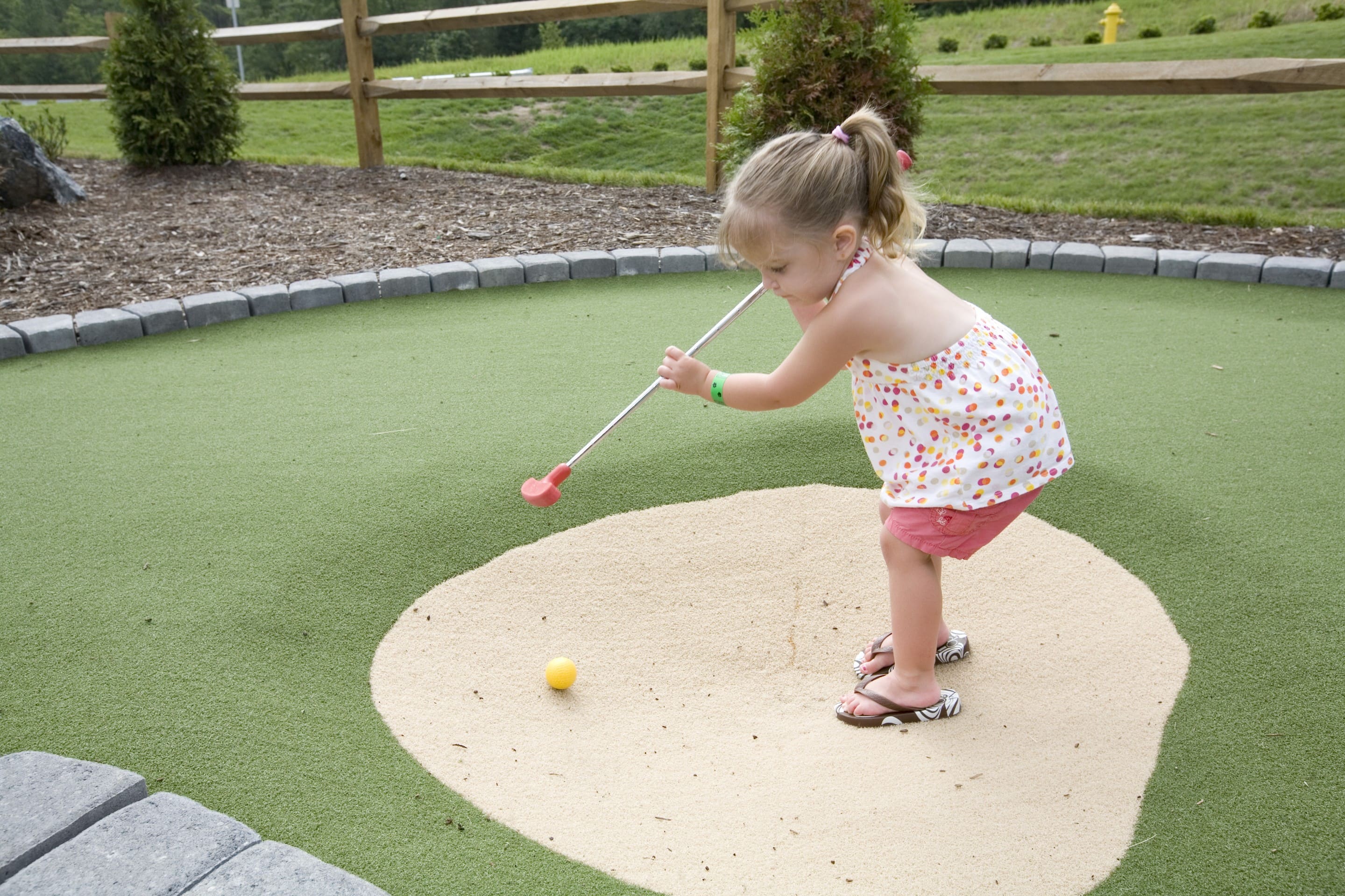A young girl attempting a putt