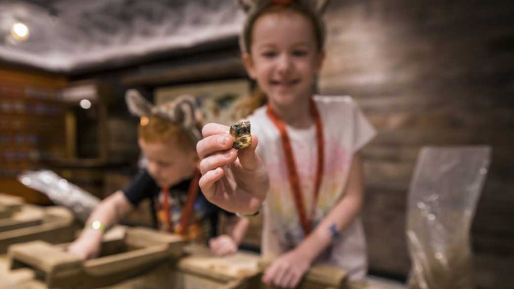 girl wearing wolf ear showing a gemstone she found while panning