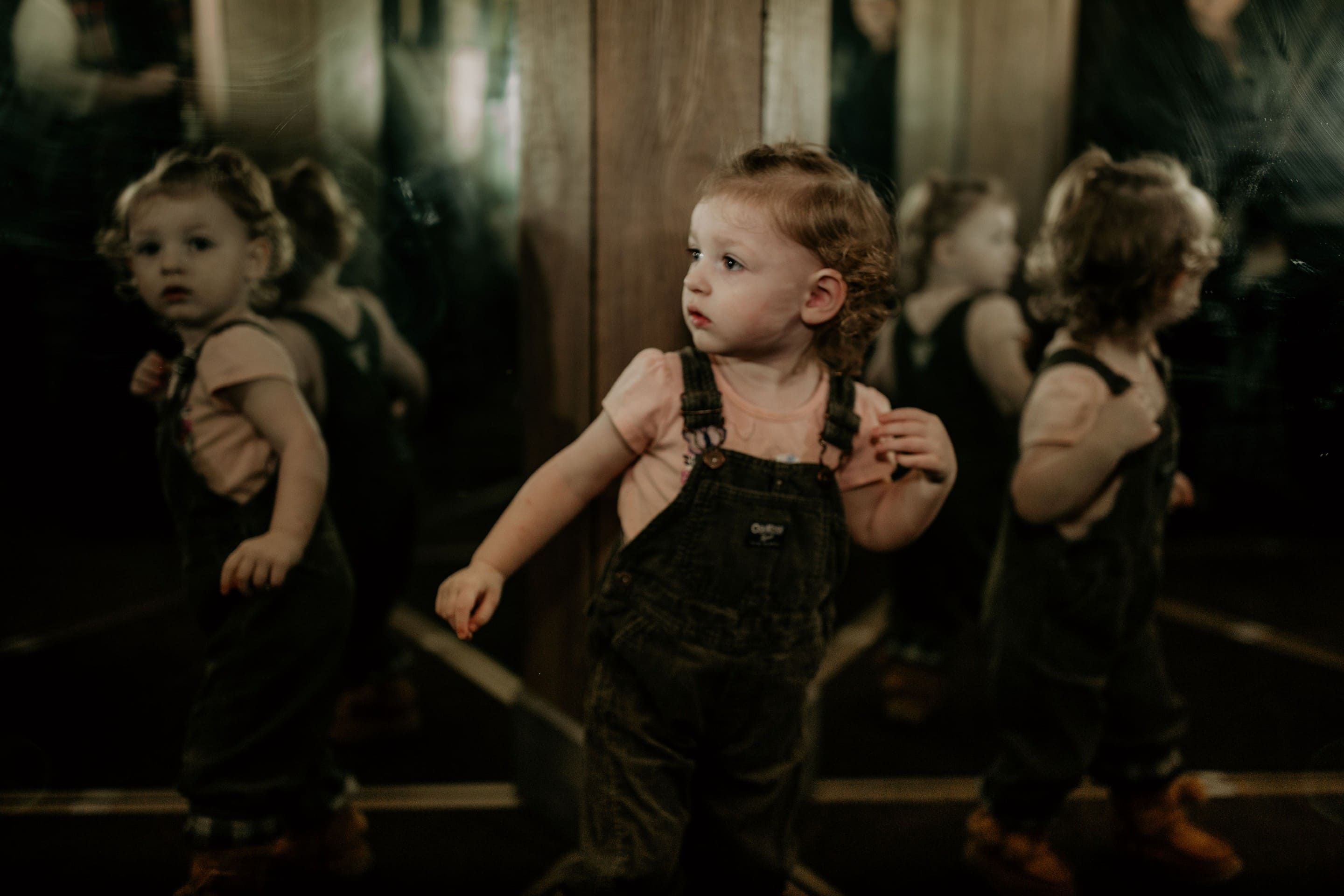 Young child exploring mirror maze, looking confused