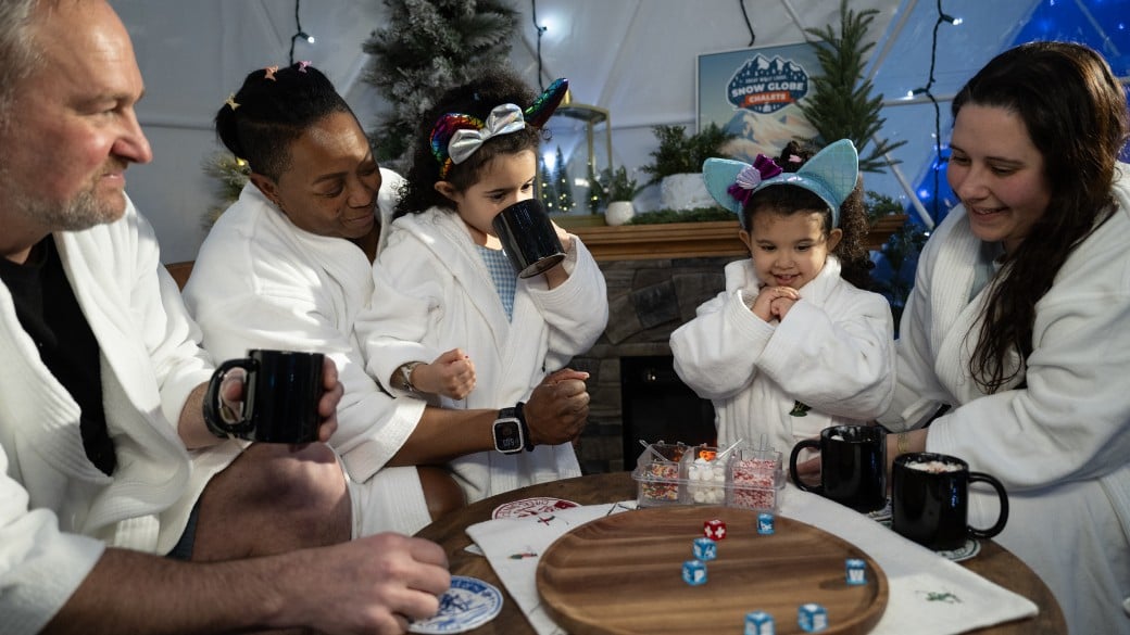 Family enjoying hot chocolate inside snow globe