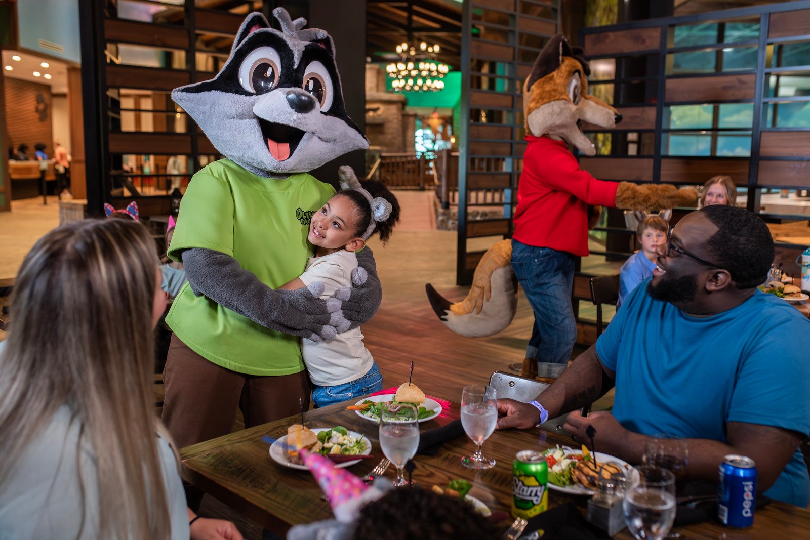 Green character visiting a family table