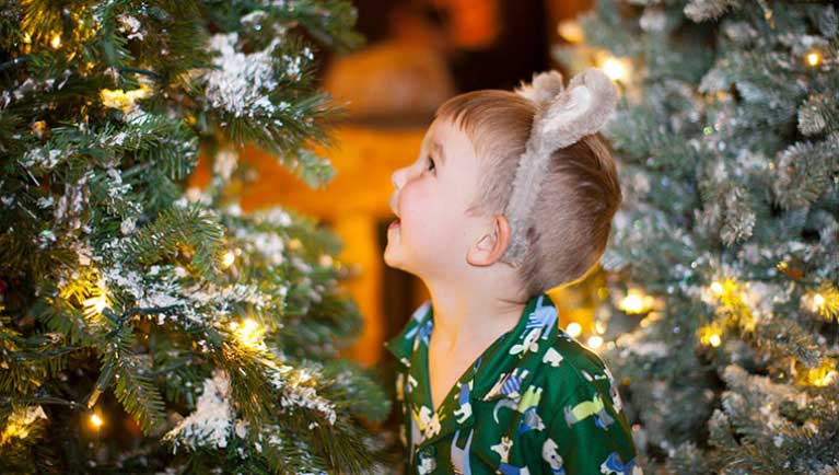 boy in pajamas looking at holiday celebration