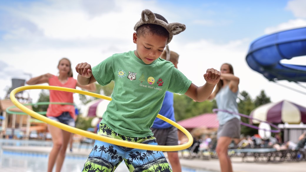 boy enjoying hoolahoop while family dances in background