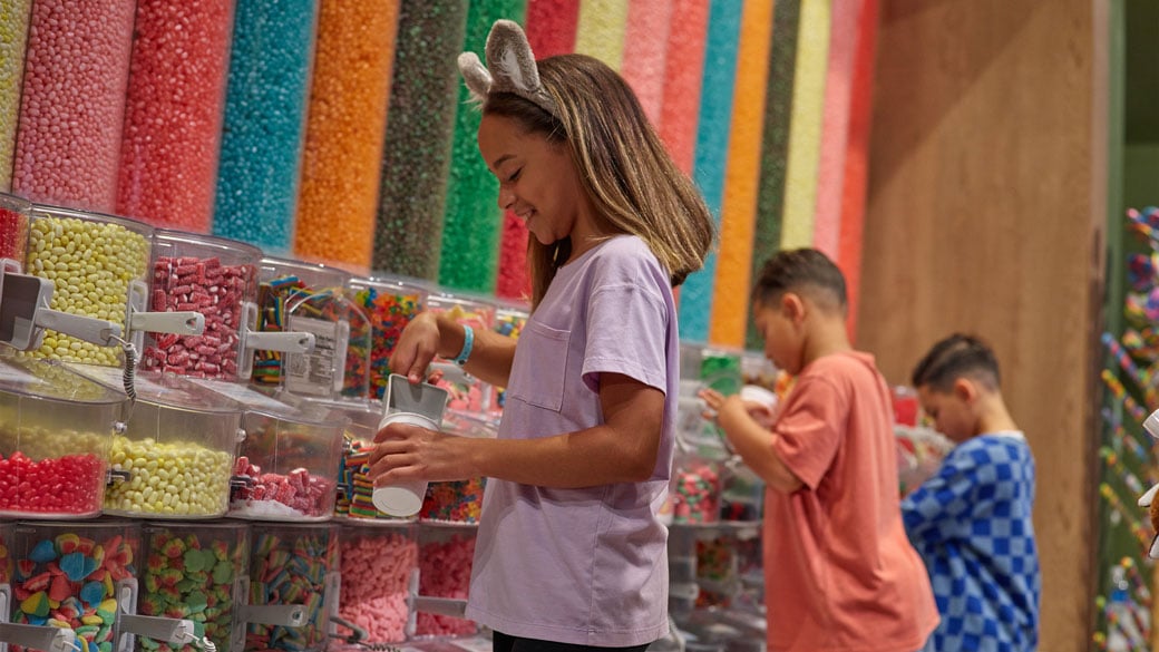girl grabbing candy at candy store