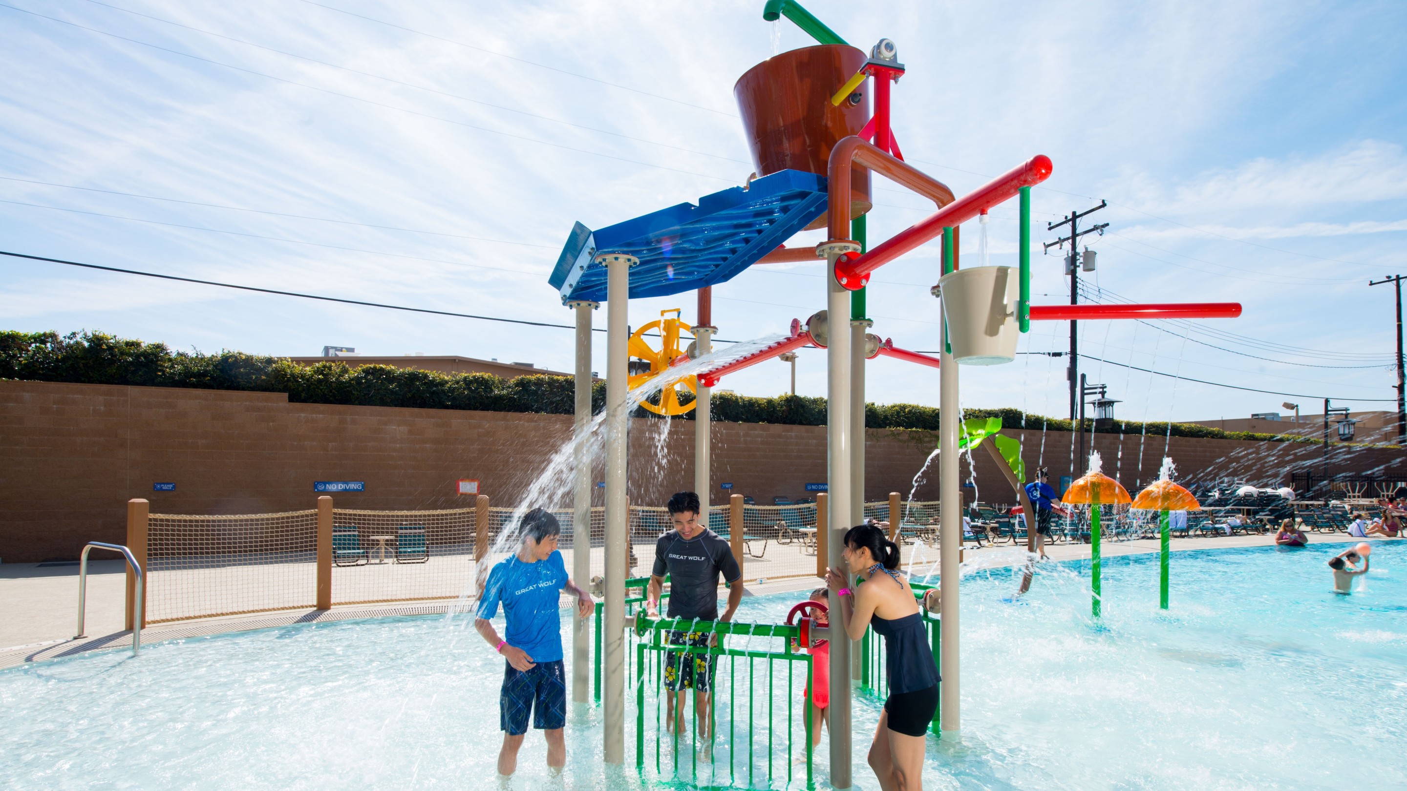 kids playing under an outdoor water park feature