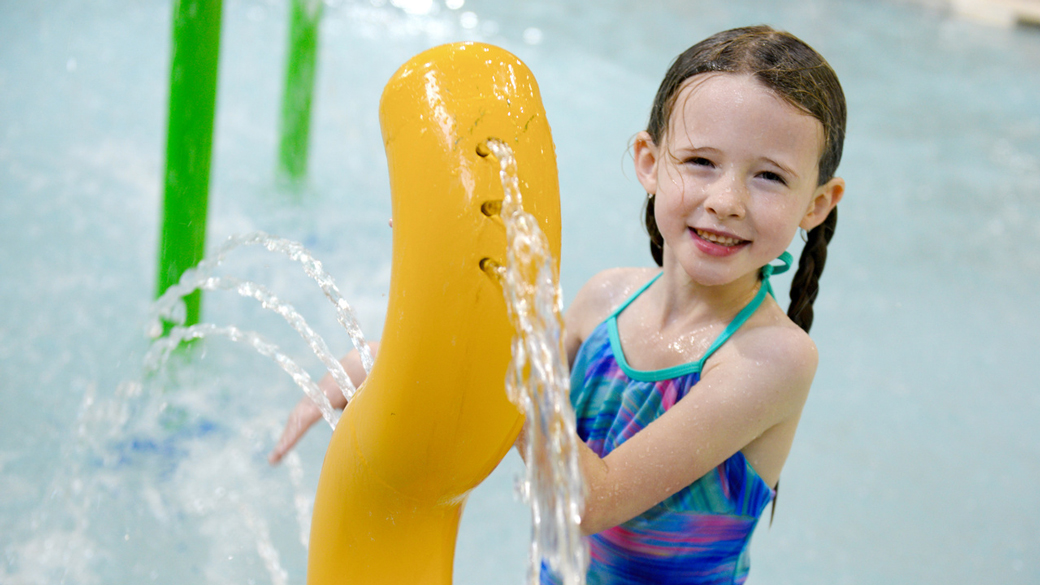 Kid playing with water in an outdoor pool