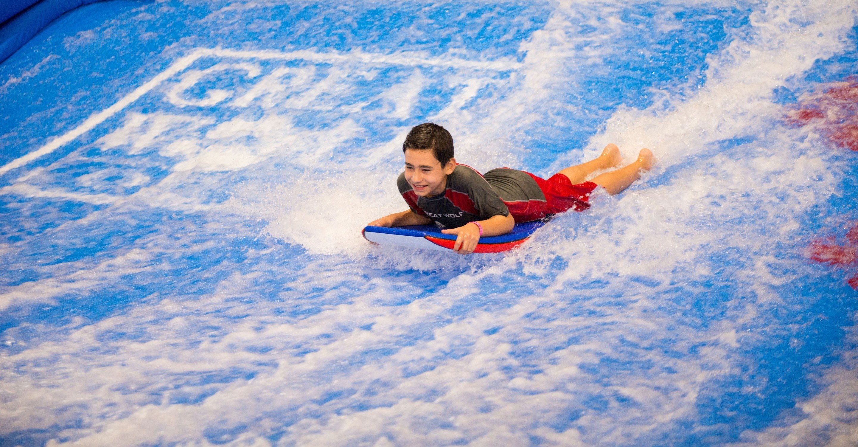 A boy on a blue boogie board going down the slide