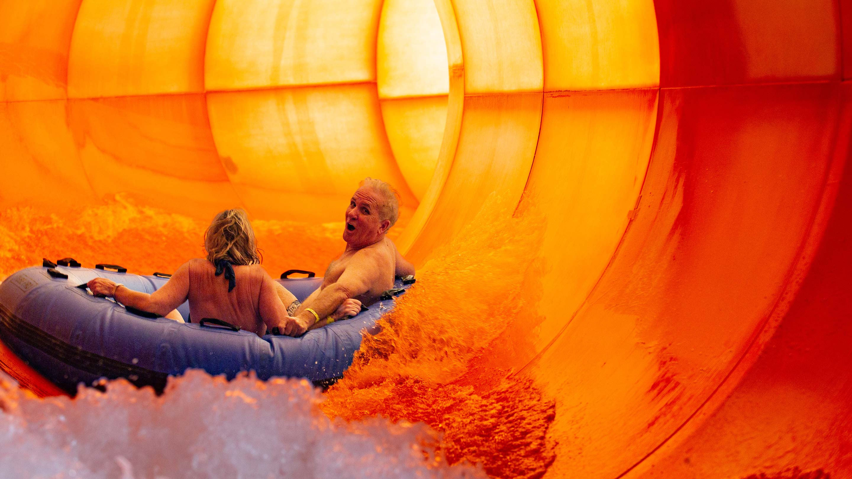 elderly couple enjoying a raft slide in an indoor water park