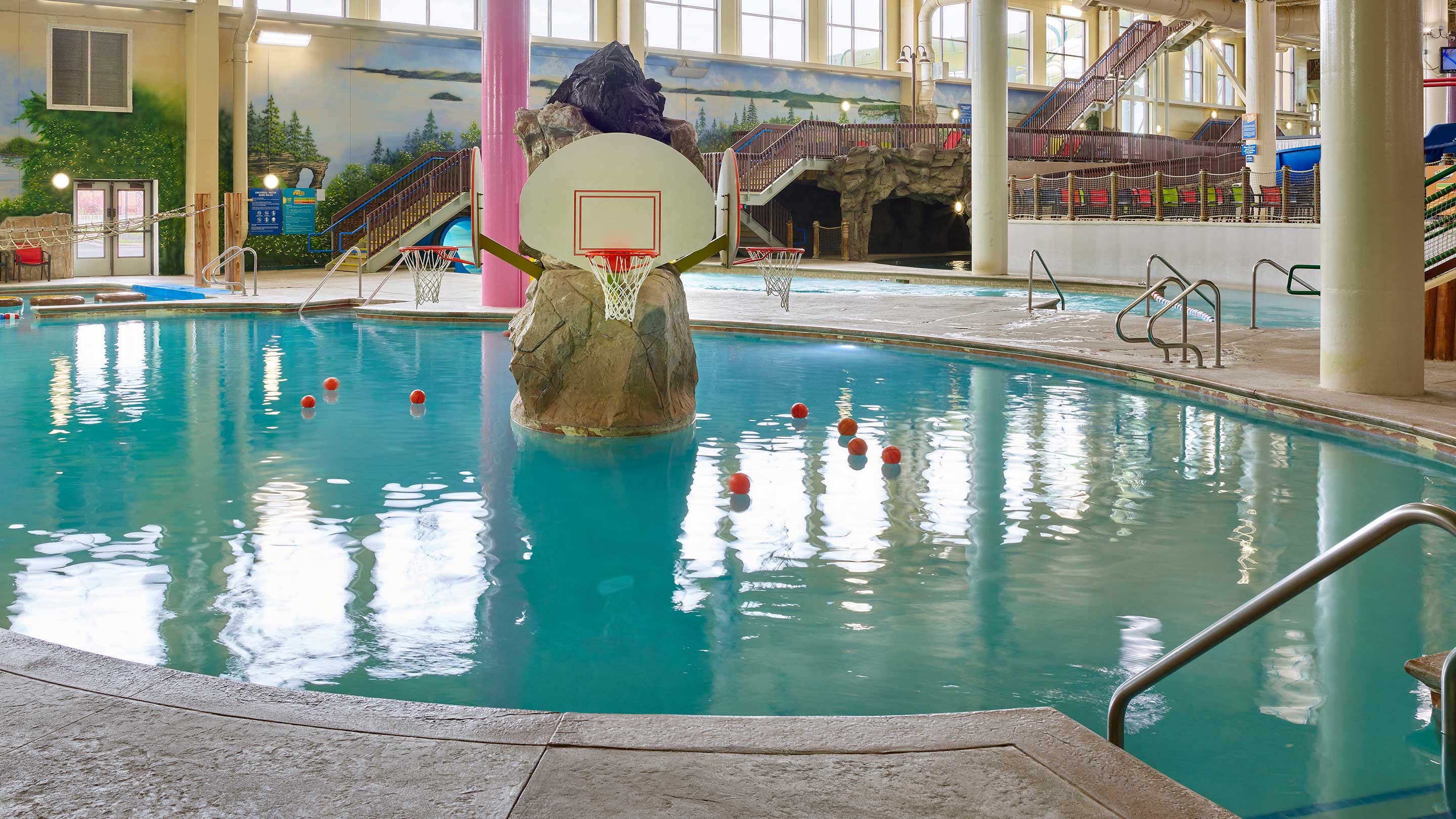 Basketball hoop and water slides in indoor pool