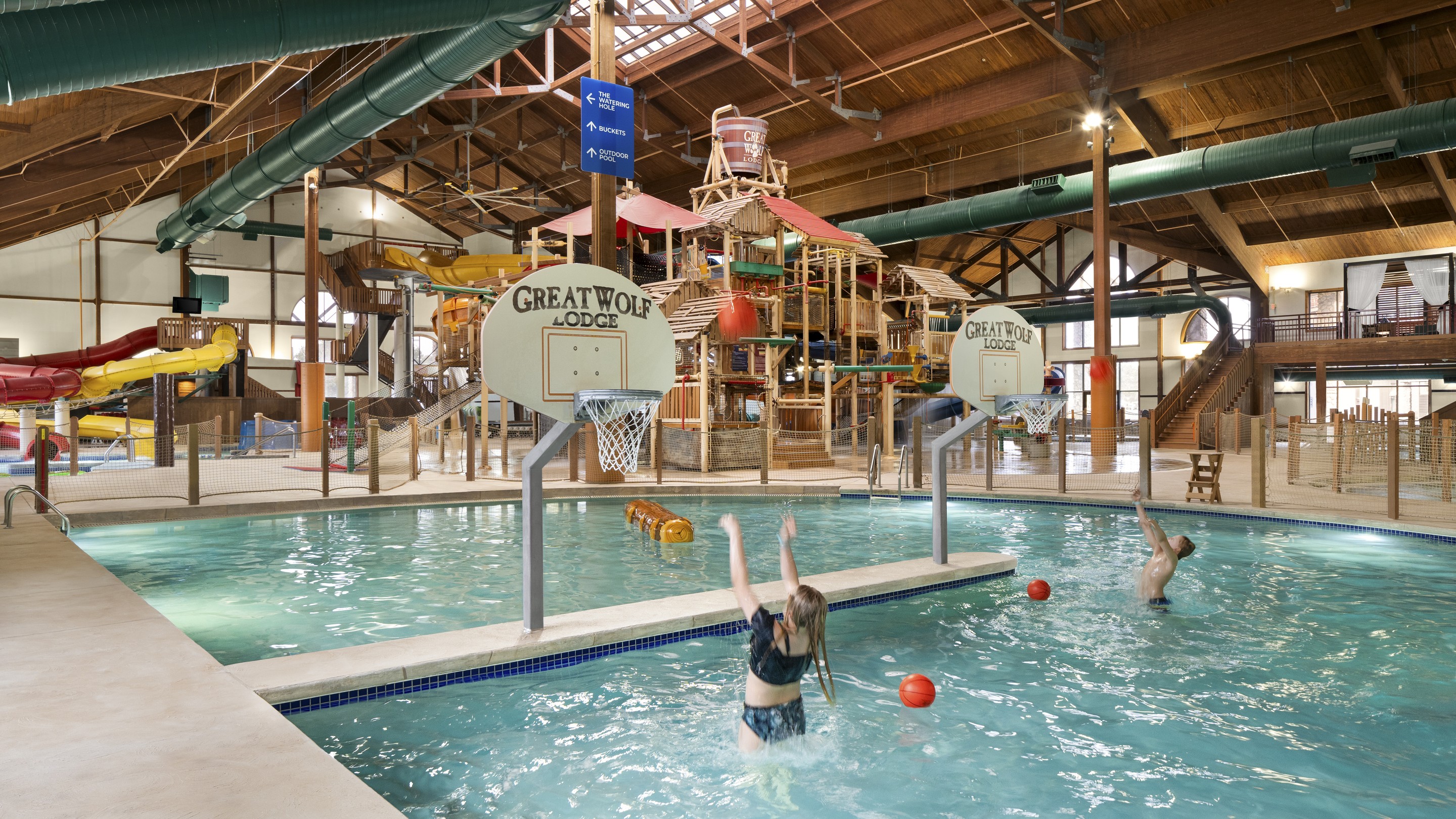 Family playing basketball in a large indoor water park