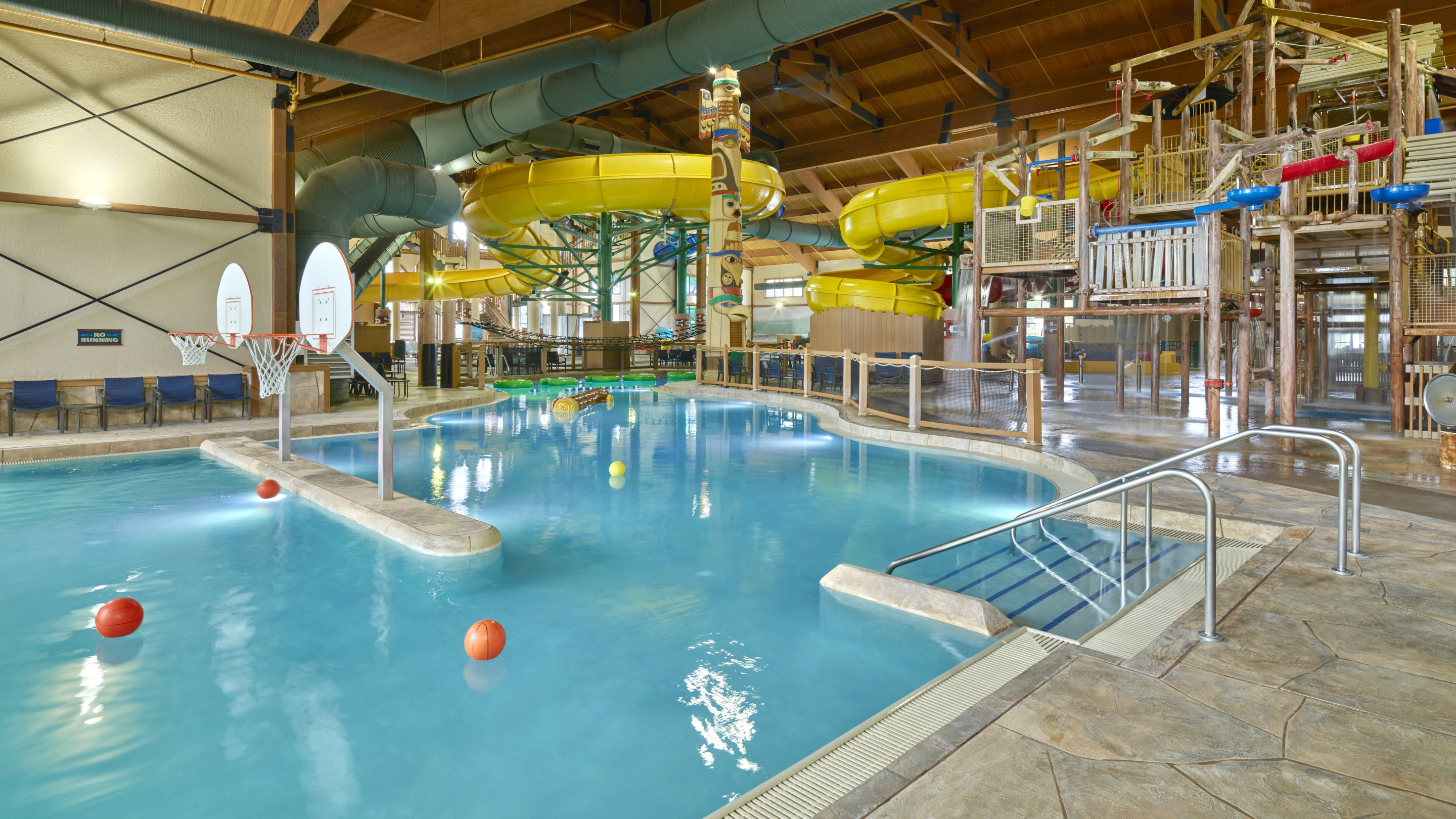 A spacious indoor pool featuring a large slide and multiple water slides