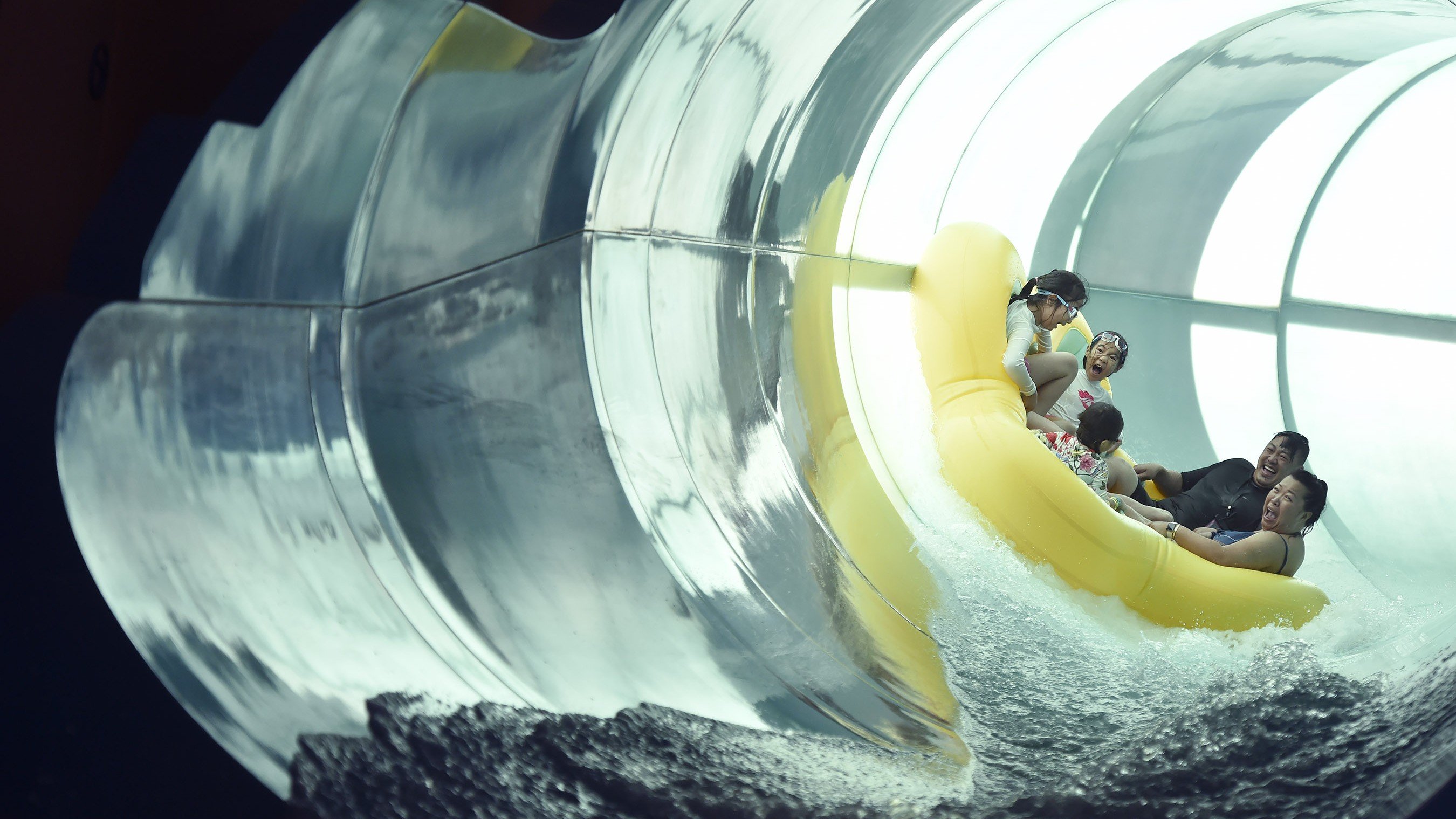 family of five on a yellow raft going down a water slide