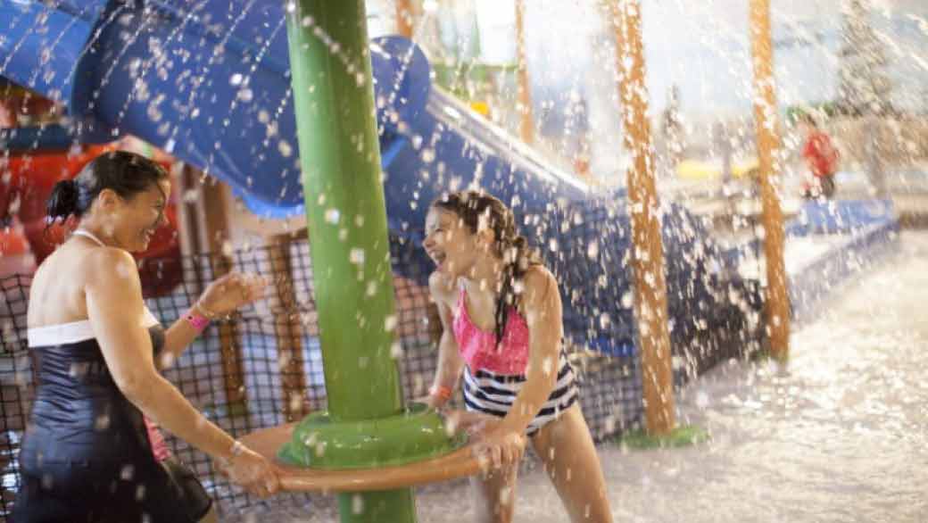 A mother and daughter having fun at Cub Paw Pool located in a Great Wolf Lodge indoor water park and resort.