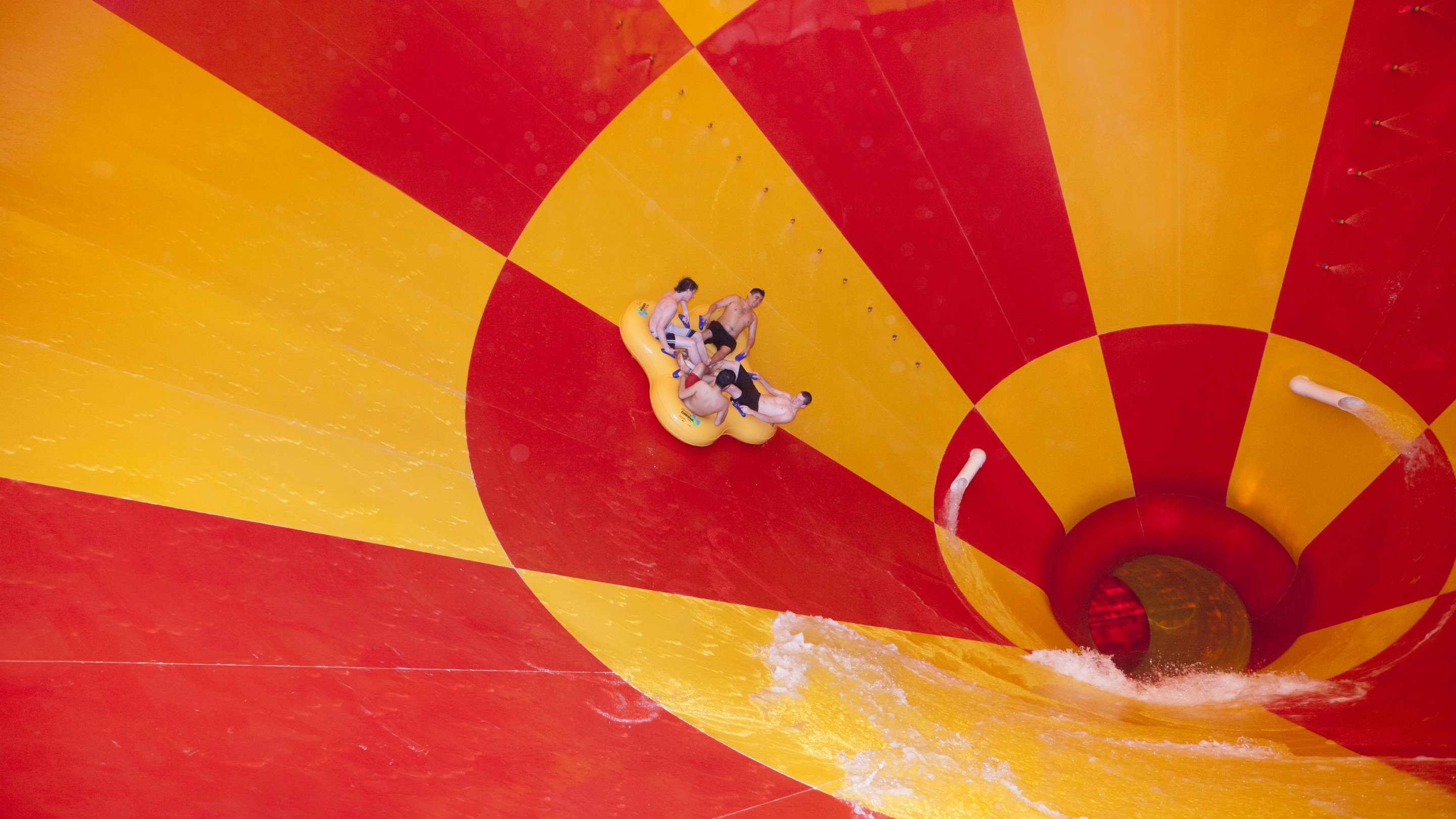 Side angle of people in inner tube sliding down the Howlin' Tornado funnel slide