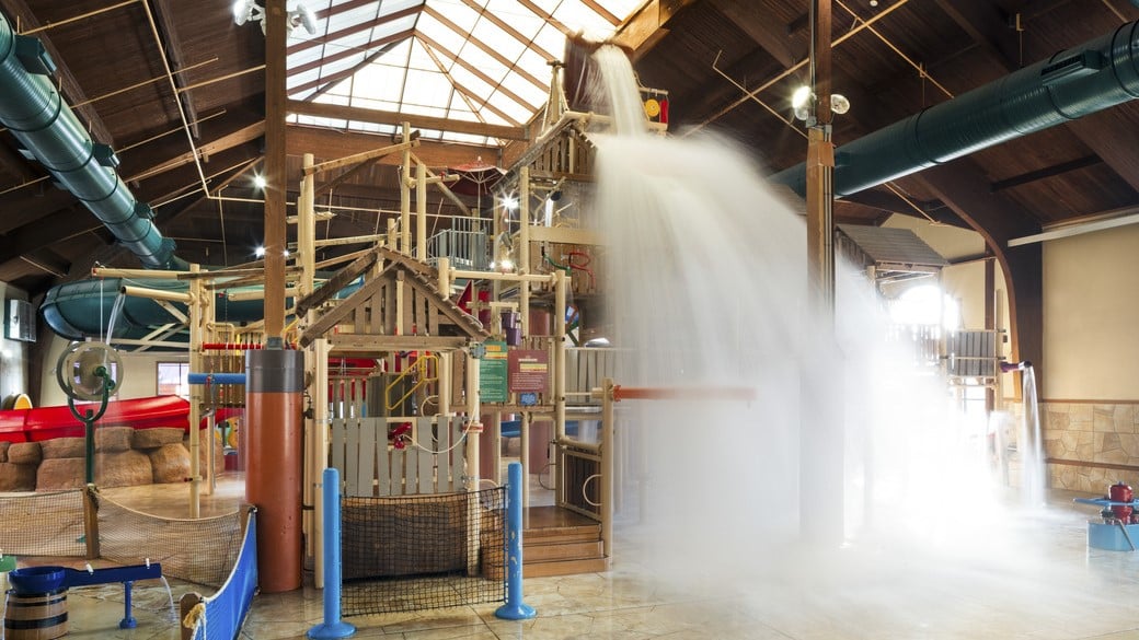 A wide shot of the  water treehouse as water splashes down from a bucket above the jungle gym