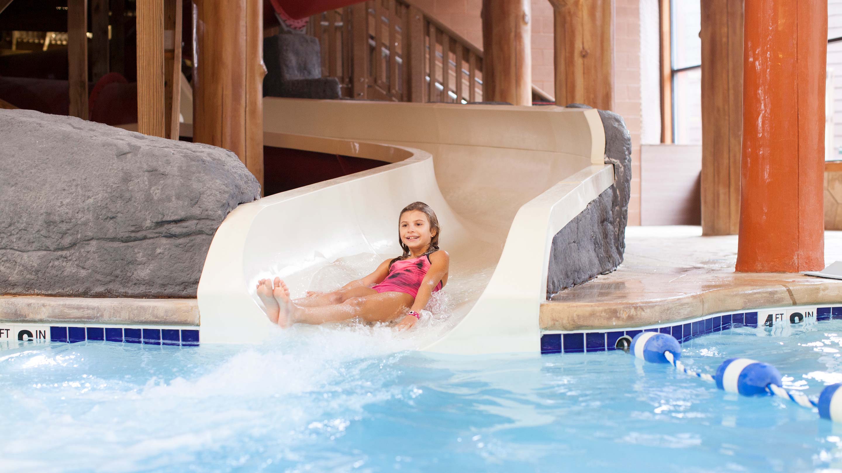 A girl going down a water slide in a pink bathing suit
