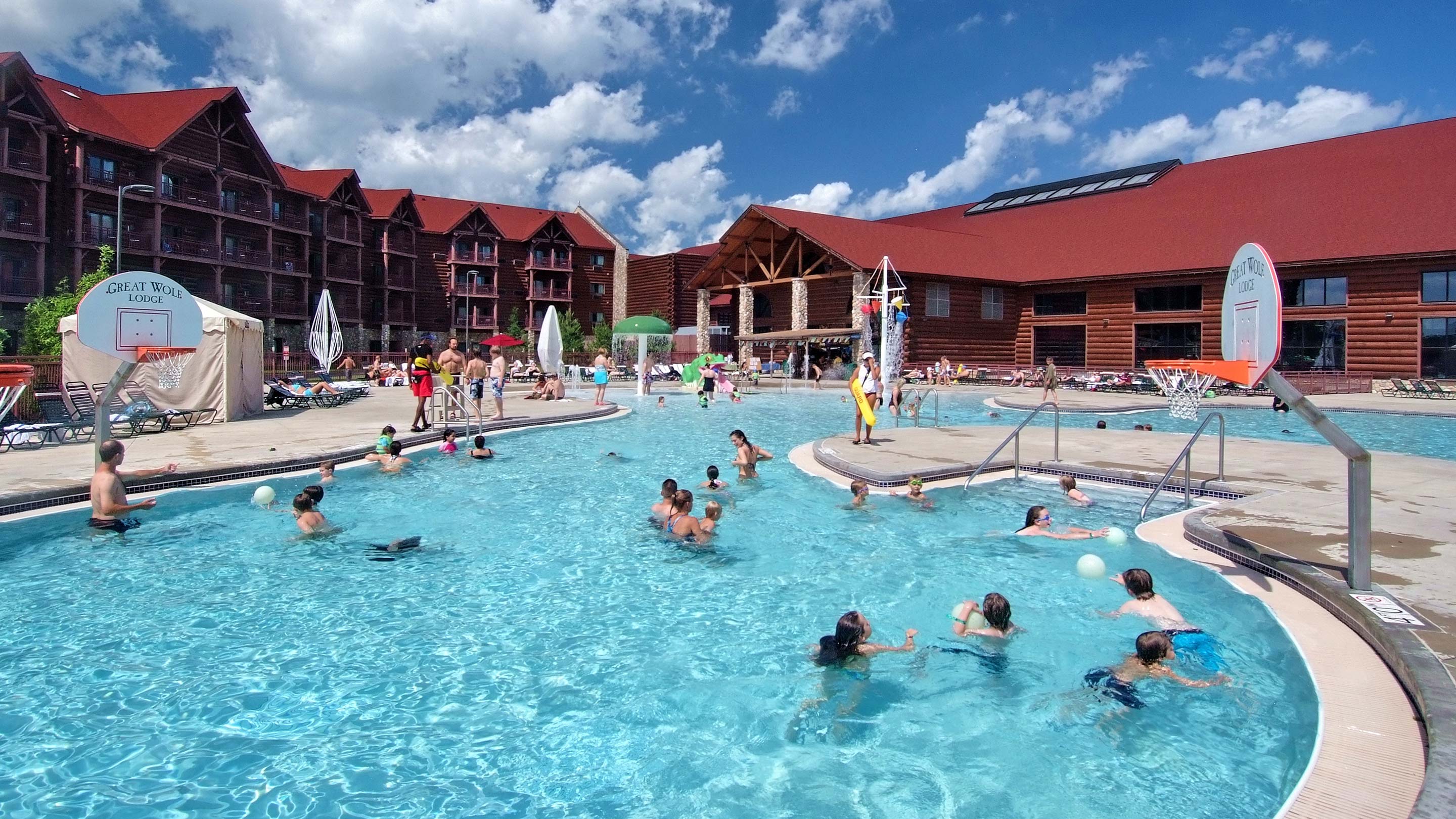 guests enjoying an outdoor play area playing basketball in the pool