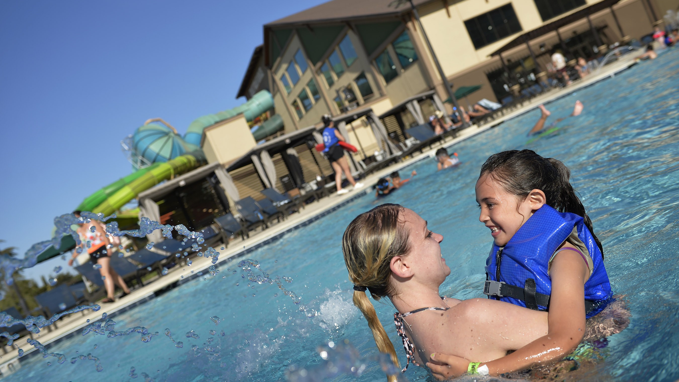 mother holding daughter in an outdoor swimming pool