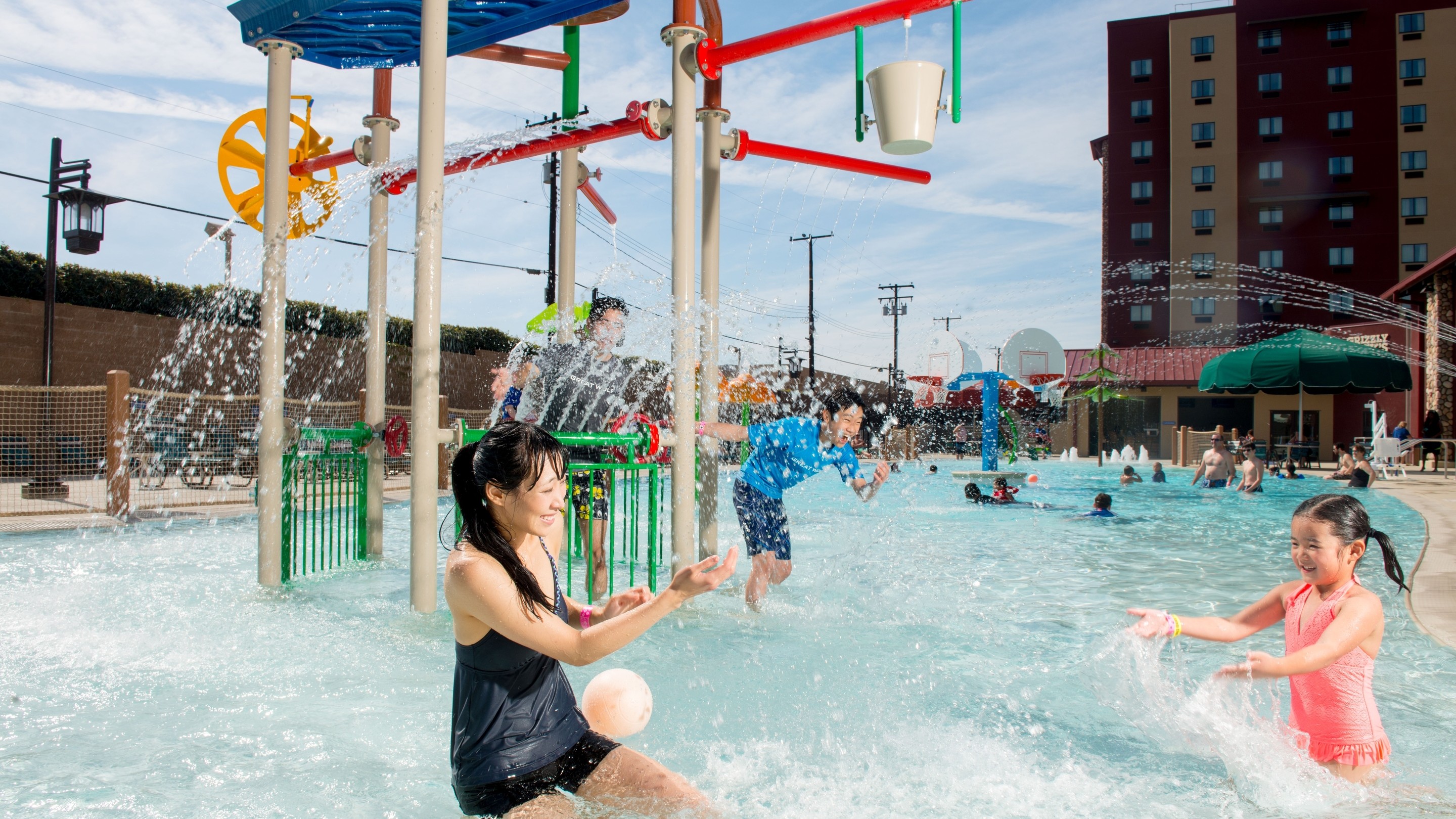mother and daughter splashing water in an outdoor pool