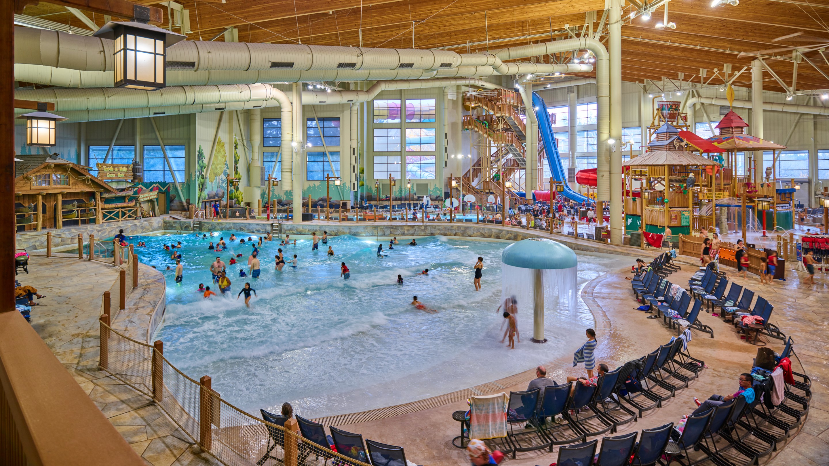 wide shot of various people playing in the wave pool