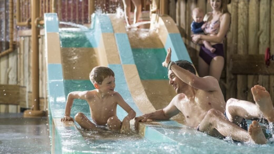 A father and son comes down from a water slide 