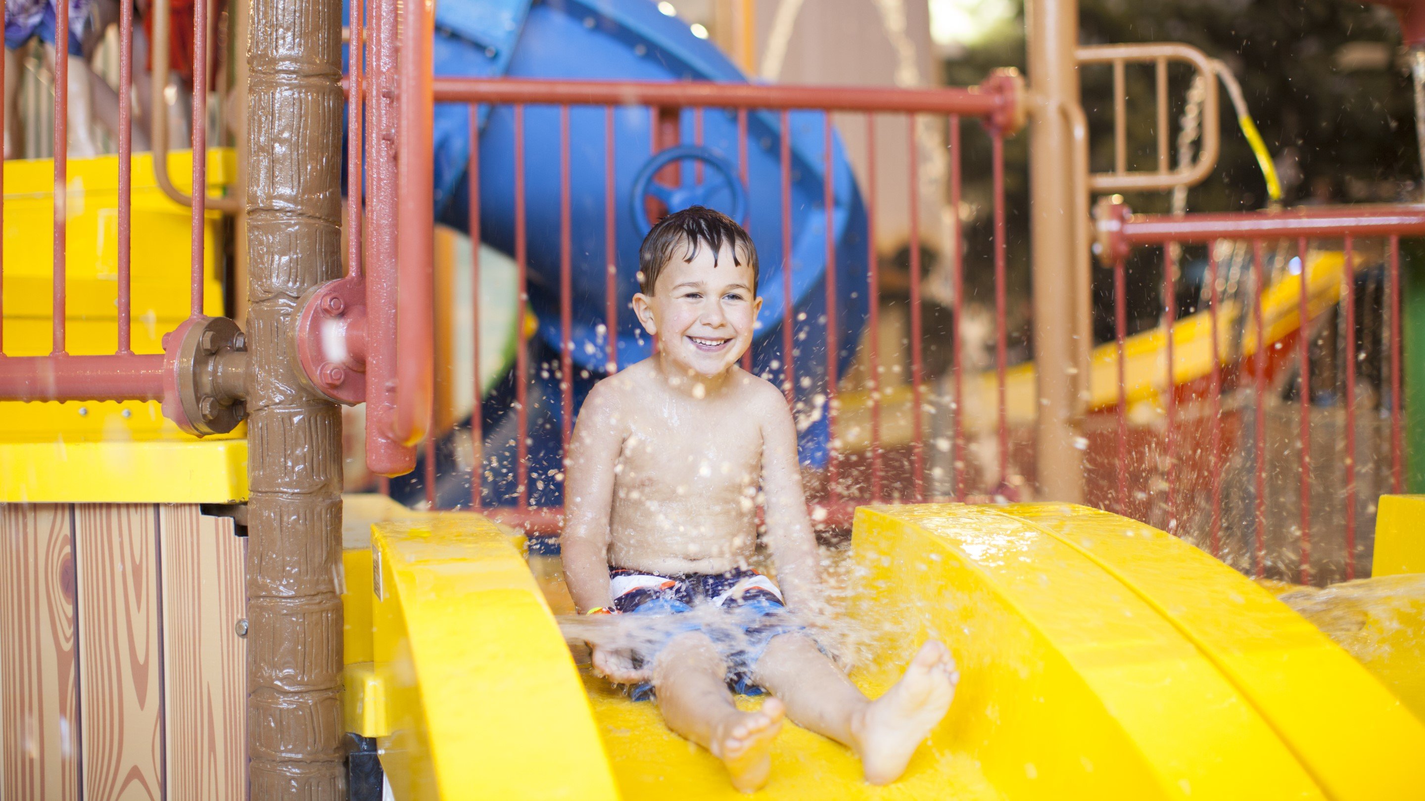 little boy about to go down a yellow water slide