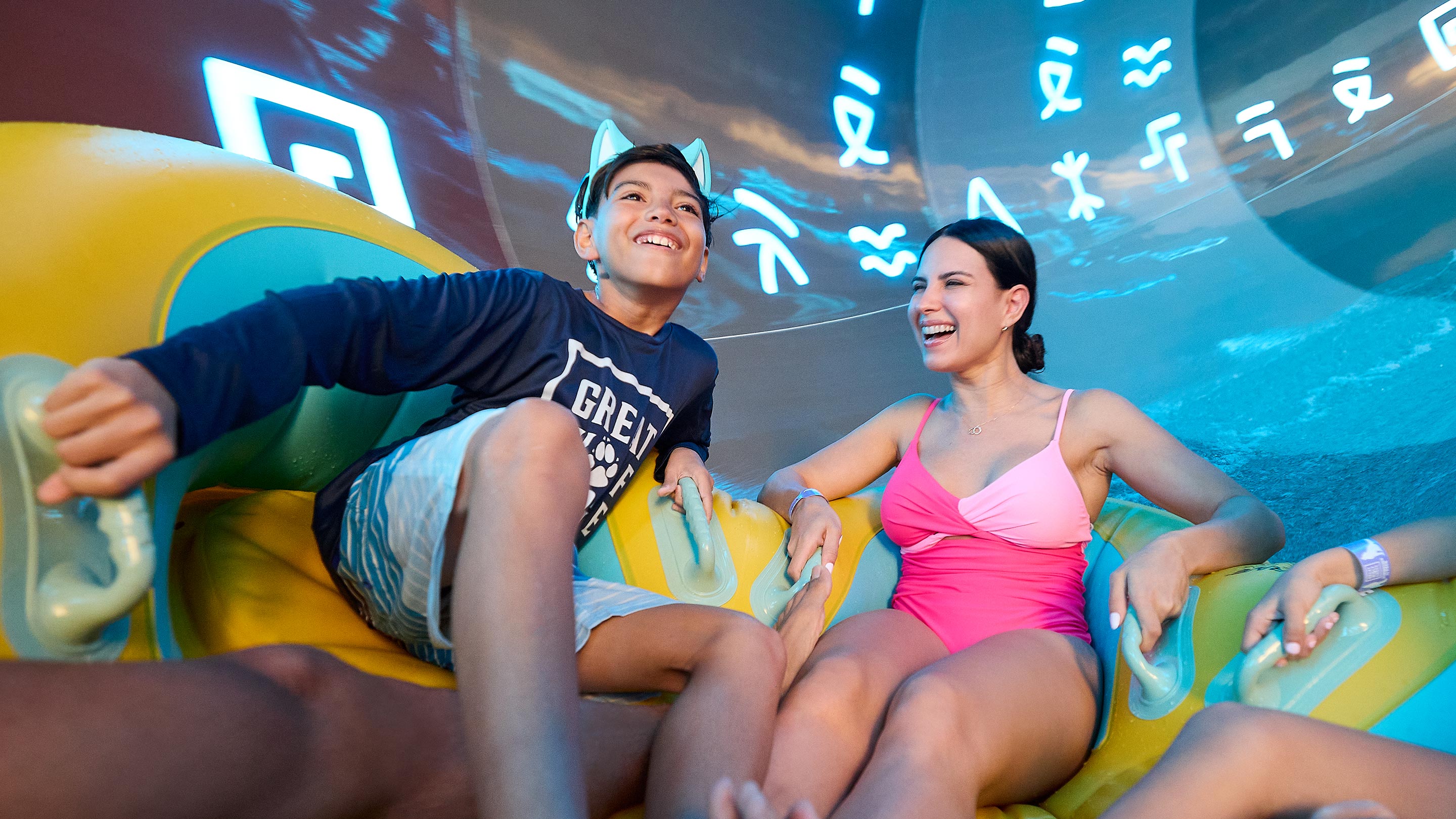 mother and son going down a water slide on a yellow and blue tube